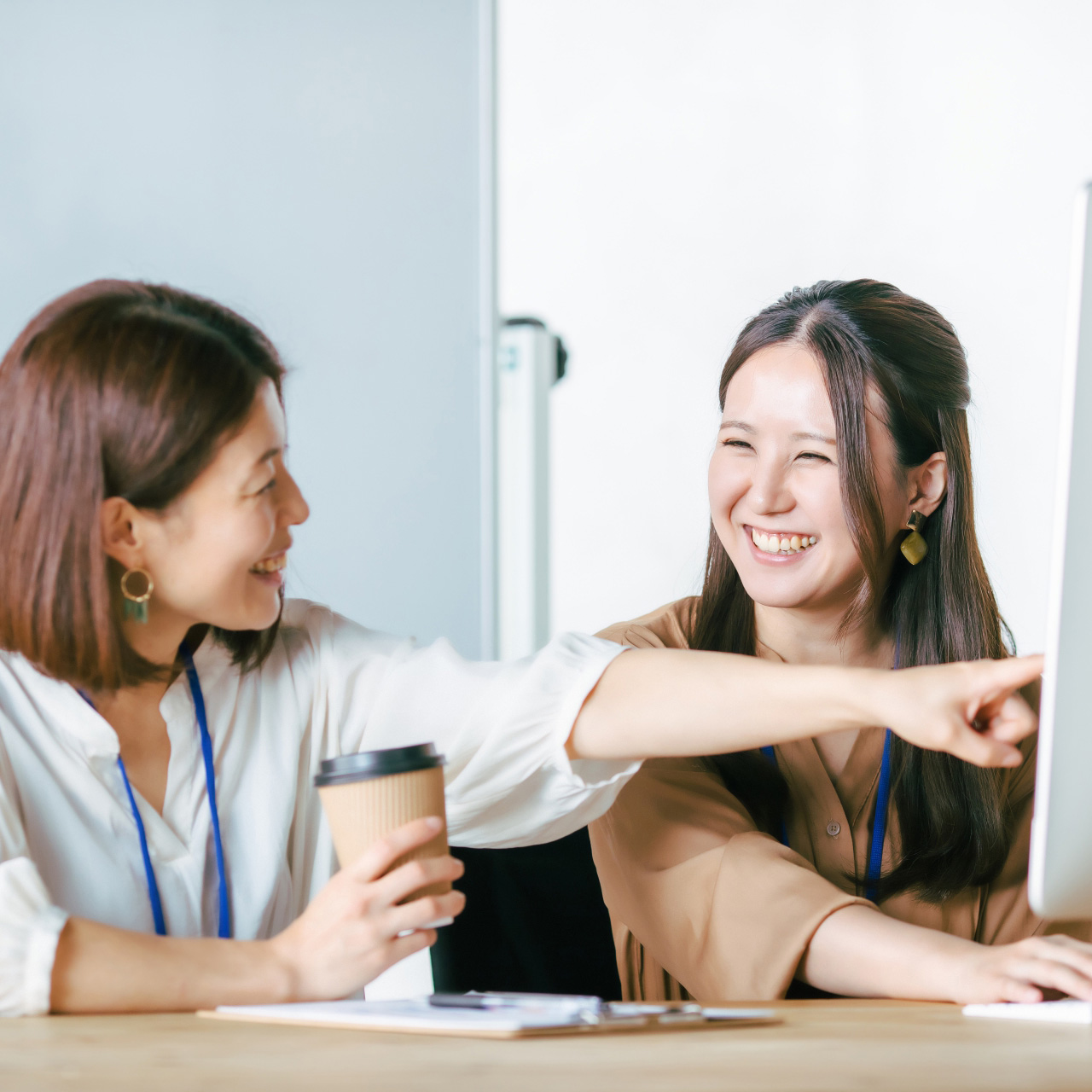 女性職員２人がパソコンを確認しながら笑顔で作業中の写真